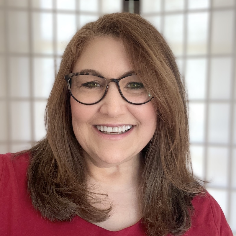 brunette woman in glasses smiling at the camera